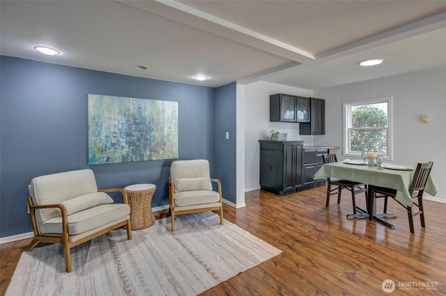 living area with beamed ceiling, baseboards, and dark wood-style flooring