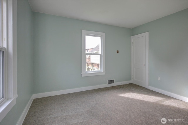 carpeted empty room featuring baseboards and visible vents