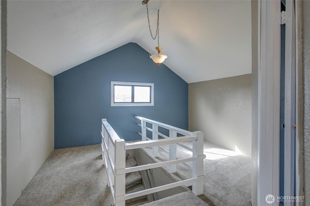 bonus room with carpet flooring, a textured wall, and vaulted ceiling