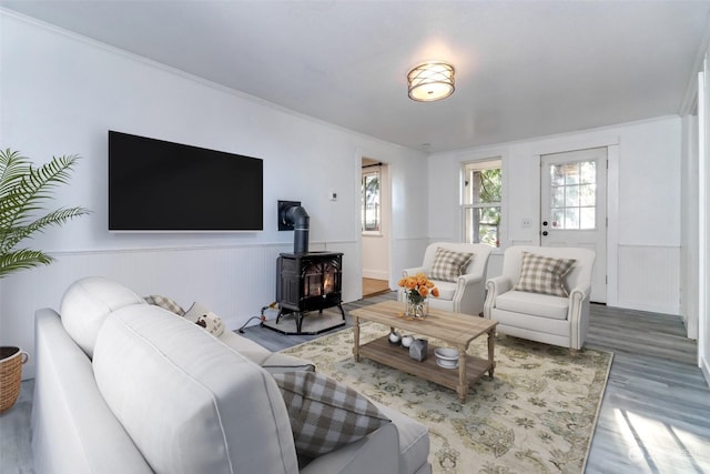 living room featuring crown molding, wood-type flooring, and a wood stove