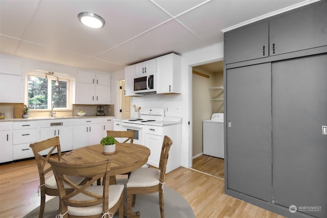 kitchen with white appliances, light hardwood / wood-style floors, decorative backsplash, white cabinets, and washer / dryer