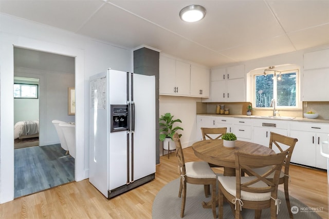 kitchen featuring white fridge with ice dispenser, sink, white cabinets, and light hardwood / wood-style floors