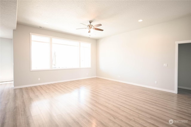 empty room with ceiling fan, a textured ceiling, and light wood-type flooring