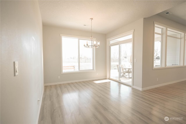 interior space featuring a textured ceiling, a chandelier, and light hardwood / wood-style floors