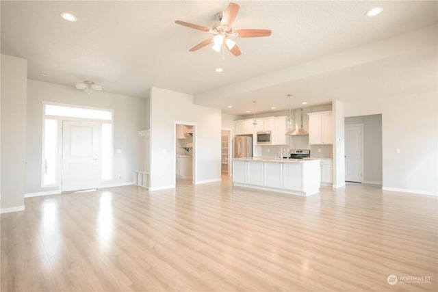 unfurnished living room featuring ceiling fan and light wood-type flooring