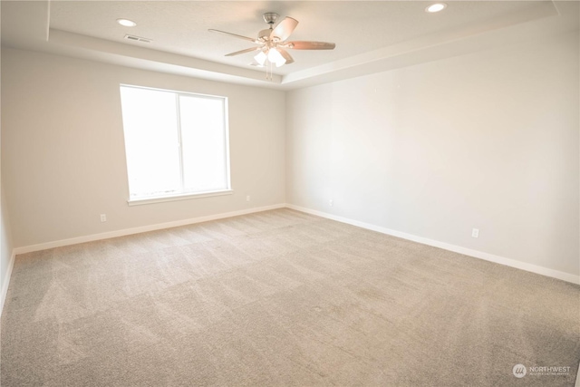 carpeted empty room featuring a raised ceiling and ceiling fan