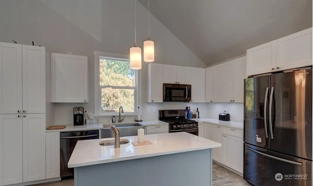 kitchen featuring decorative light fixtures, sink, appliances with stainless steel finishes, an island with sink, and white cabinets