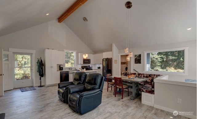 living room with high vaulted ceiling, a wealth of natural light, beamed ceiling, and light wood-type flooring