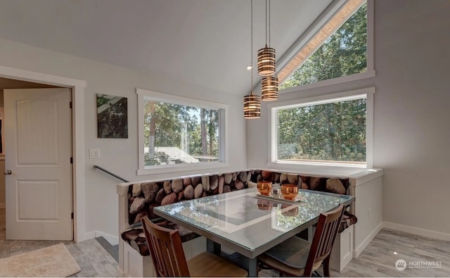 dining space featuring breakfast area, lofted ceiling, and light wood-type flooring