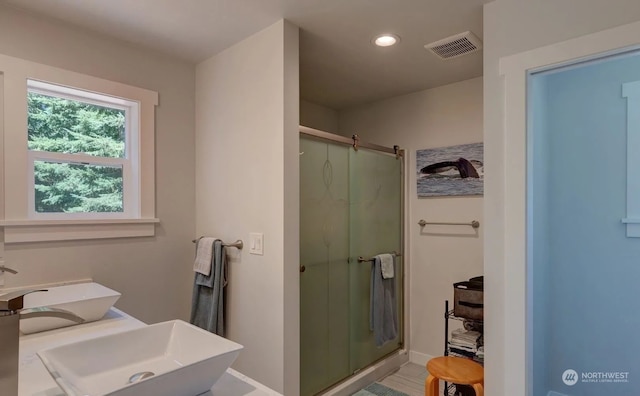 bathroom with double sink and a shower with door