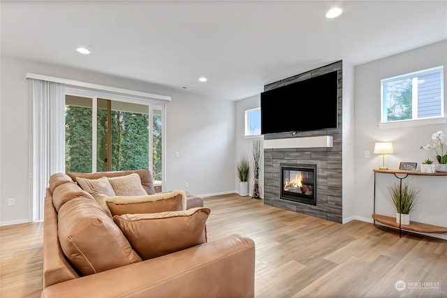 living room with light wood-type flooring and a tiled fireplace