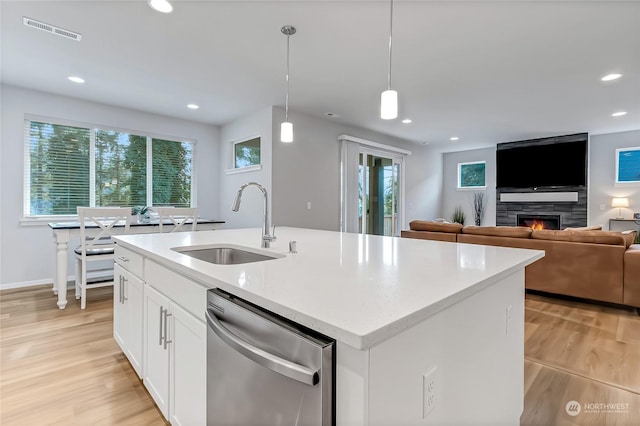 kitchen featuring dishwasher, hanging light fixtures, sink, white cabinets, and an island with sink