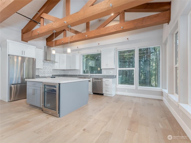 kitchen featuring white cabinetry, a kitchen island, decorative light fixtures, stainless steel appliances, and beverage cooler