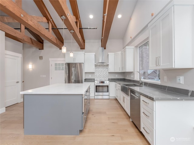 kitchen featuring a center island, stainless steel appliances, white cabinetry, and wall chimney exhaust hood