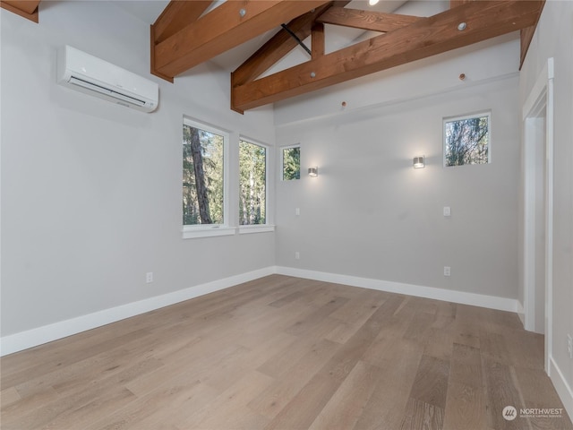 empty room featuring vaulted ceiling with beams, a wall unit AC, and light wood-type flooring