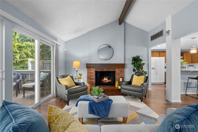 living room featuring a brick fireplace, wood-type flooring, a textured ceiling, and vaulted ceiling with beams