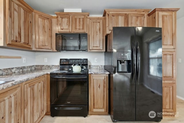 kitchen with light stone counters and black appliances