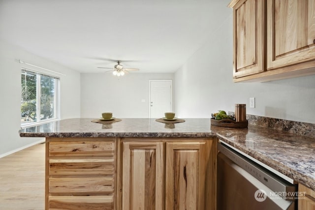 kitchen featuring light brown cabinetry, dark stone countertops, ceiling fan, kitchen peninsula, and light wood-type flooring