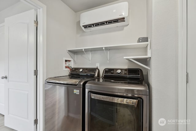 laundry area featuring an AC wall unit, independent washer and dryer, and light hardwood / wood-style flooring