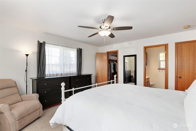 bedroom with ceiling fan, ensuite bathroom, a spacious closet, light colored carpet, and a closet