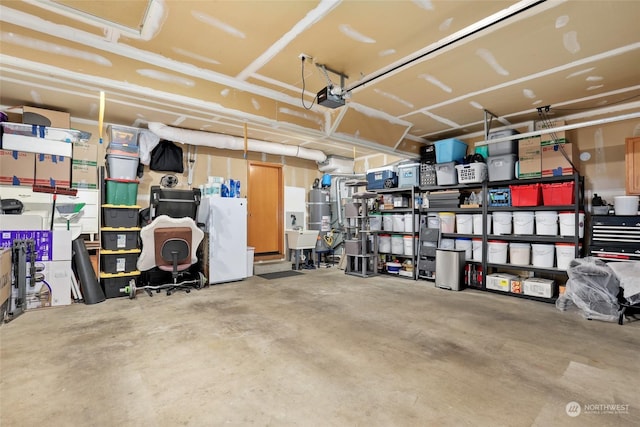 garage with a garage door opener, strapped water heater, sink, and white fridge