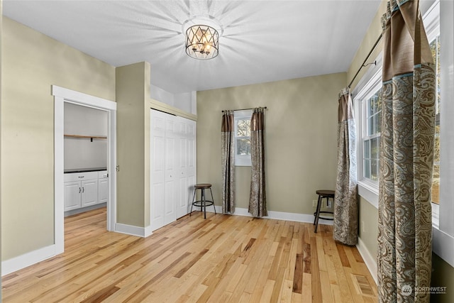 interior space with light hardwood / wood-style floors, a closet, and a notable chandelier