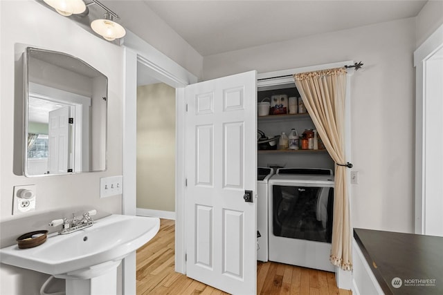 bathroom with hardwood / wood-style floors, washing machine and dryer, and sink