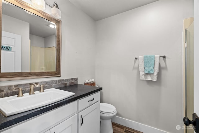 bathroom featuring vanity, hardwood / wood-style flooring, toilet, and walk in shower