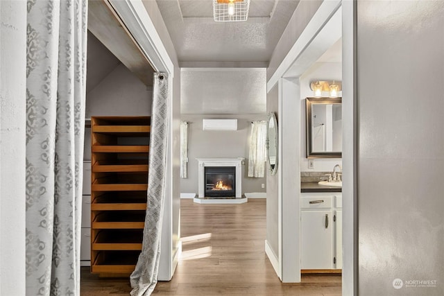 hallway featuring an AC wall unit, sink, a textured ceiling, and light hardwood / wood-style floors