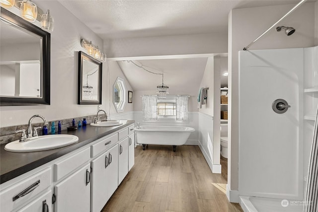 bathroom featuring hardwood / wood-style floors, vanity, a bath, a textured ceiling, and vaulted ceiling