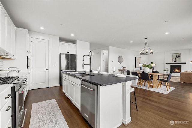 kitchen featuring sink, white cabinets, appliances with stainless steel finishes, and a center island with sink