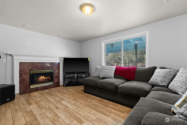 living room with a fireplace, light wood-type flooring, and a textured ceiling