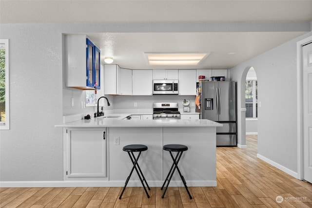 kitchen featuring white cabinets, stainless steel appliances, sink, kitchen peninsula, and a breakfast bar area