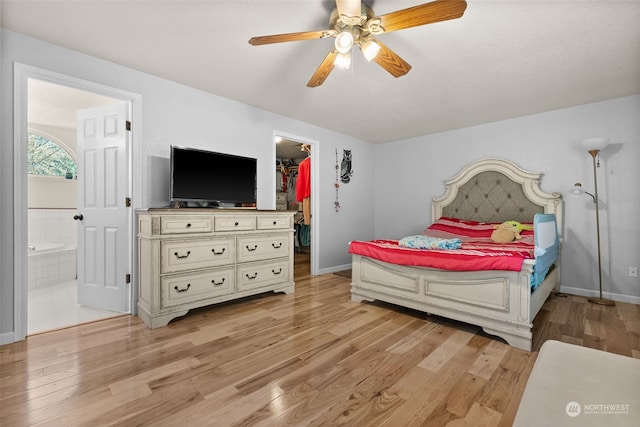 bedroom featuring ceiling fan, light hardwood / wood-style flooring, connected bathroom, and a spacious closet