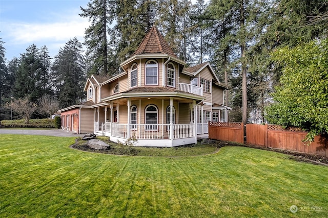 victorian home with covered porch, a garage, and a front lawn