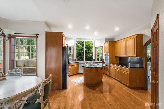 kitchen with stainless steel appliances, backsplash, a center island, and light hardwood / wood-style flooring