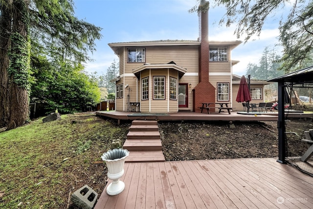 back of property featuring a deck and a gazebo