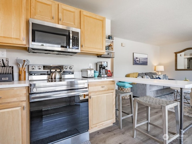 kitchen featuring appliances with stainless steel finishes, wood-type flooring, and light brown cabinets