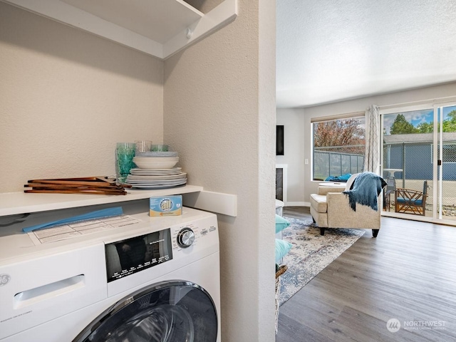 clothes washing area with hardwood / wood-style flooring and washer / clothes dryer