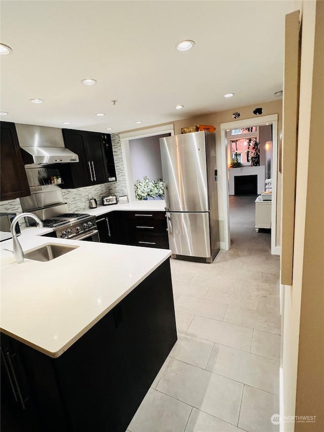 kitchen with sink, light tile patterned floors, wall chimney range hood, decorative backsplash, and stainless steel appliances