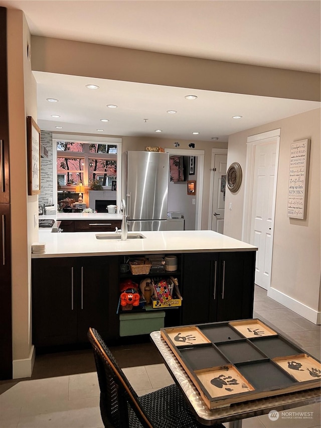 kitchen with sink, dark tile patterned floors, and stainless steel fridge