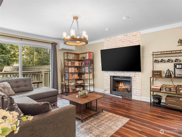 living room with a wall unit AC, a brick fireplace, dark wood-type flooring, a chandelier, and crown molding