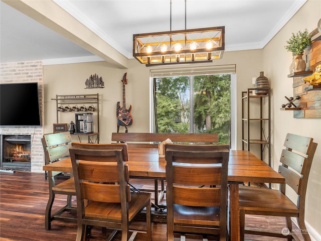 dining room with dark hardwood / wood-style flooring, ornamental molding, a notable chandelier, and a fireplace