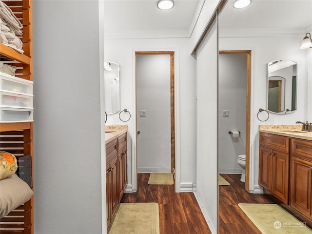 bathroom with toilet, crown molding, wood-type flooring, and vanity