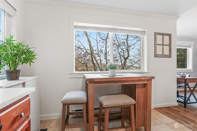 dining space featuring light tile patterned floors, crown molding, and a healthy amount of sunlight