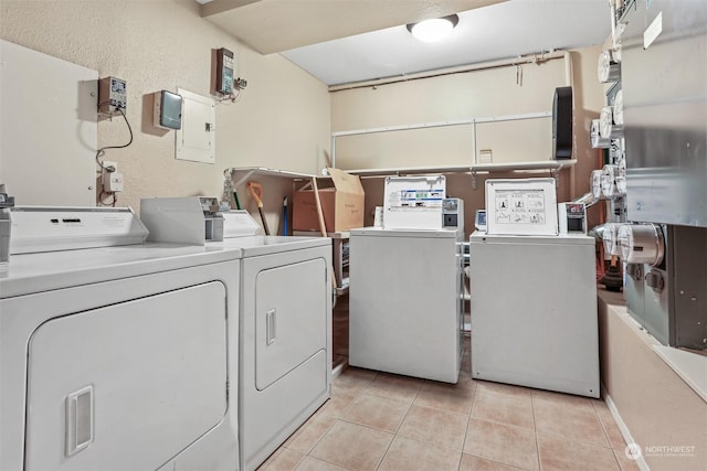 washroom with electric panel, separate washer and dryer, and light tile patterned floors