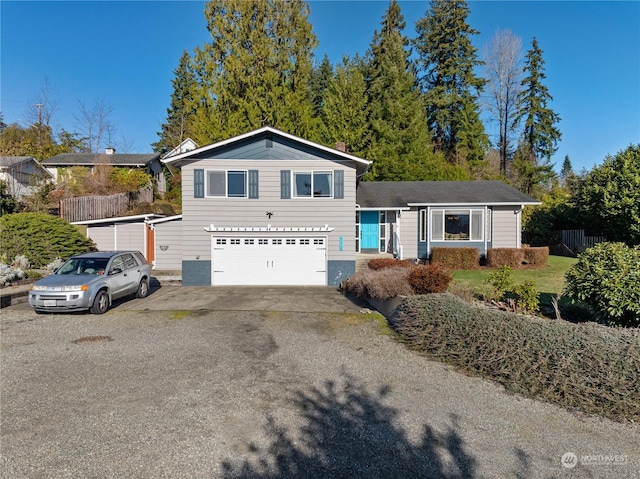 view of front facade featuring aphalt driveway, central AC unit, an attached garage, and fence