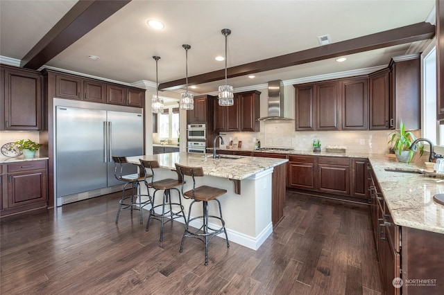 kitchen featuring a sink, beamed ceiling, appliances with stainless steel finishes, and wall chimney range hood