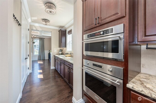 kitchen with baseboards, ornamental molding, light stone counters, decorative backsplash, and dark wood-style floors