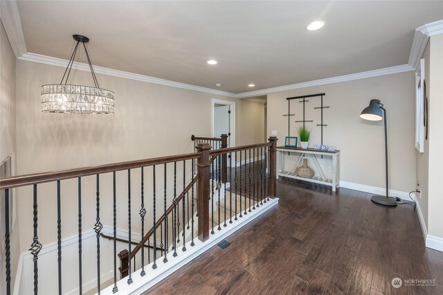 hallway featuring wood finished floors, baseboards, recessed lighting, crown molding, and an upstairs landing